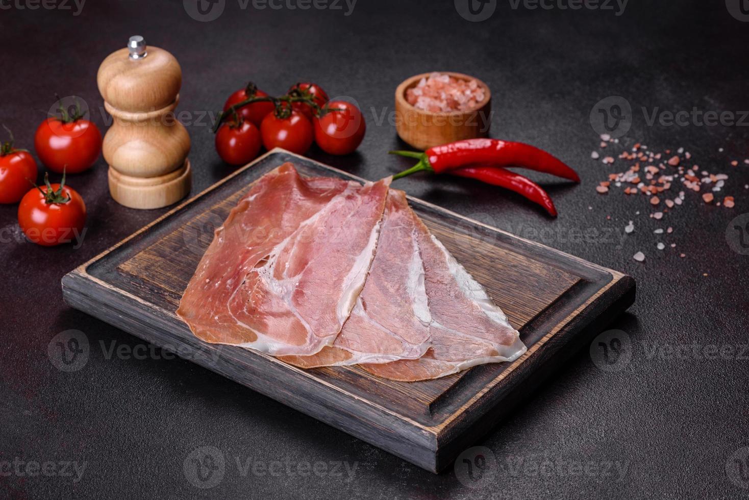 prosciutto crudo italiano o jamón español en una tabla de cortar oscura foto