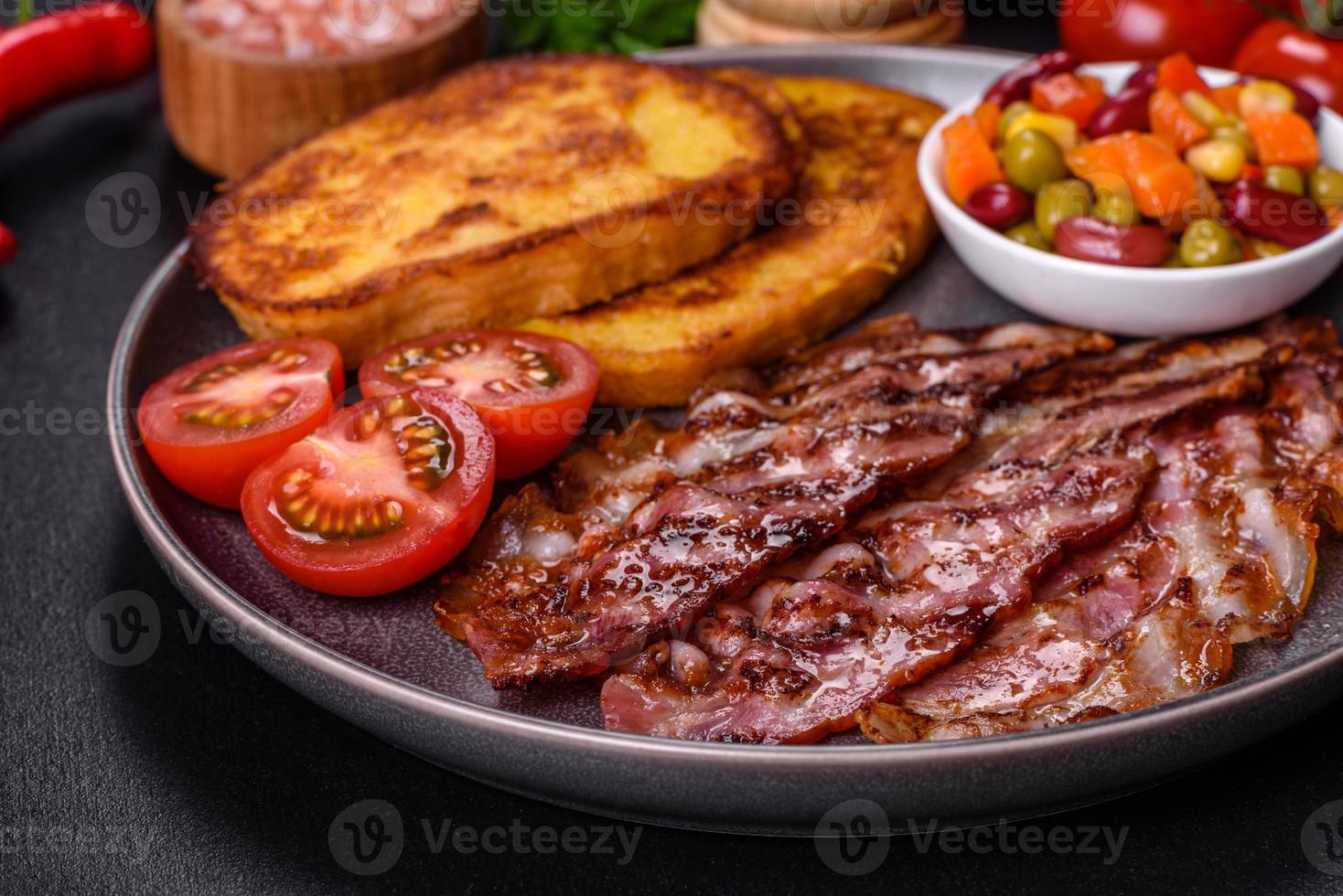 rebanadas de delicioso tocino a la parrilla con picatostes fritos en huevo con especias, sal, verduras y hierbas foto