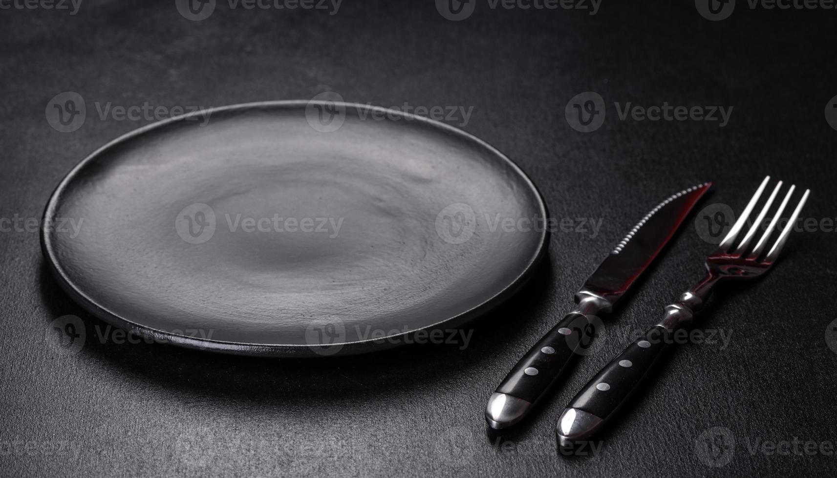 Empty round black plate on dark moody black background with copy space photo