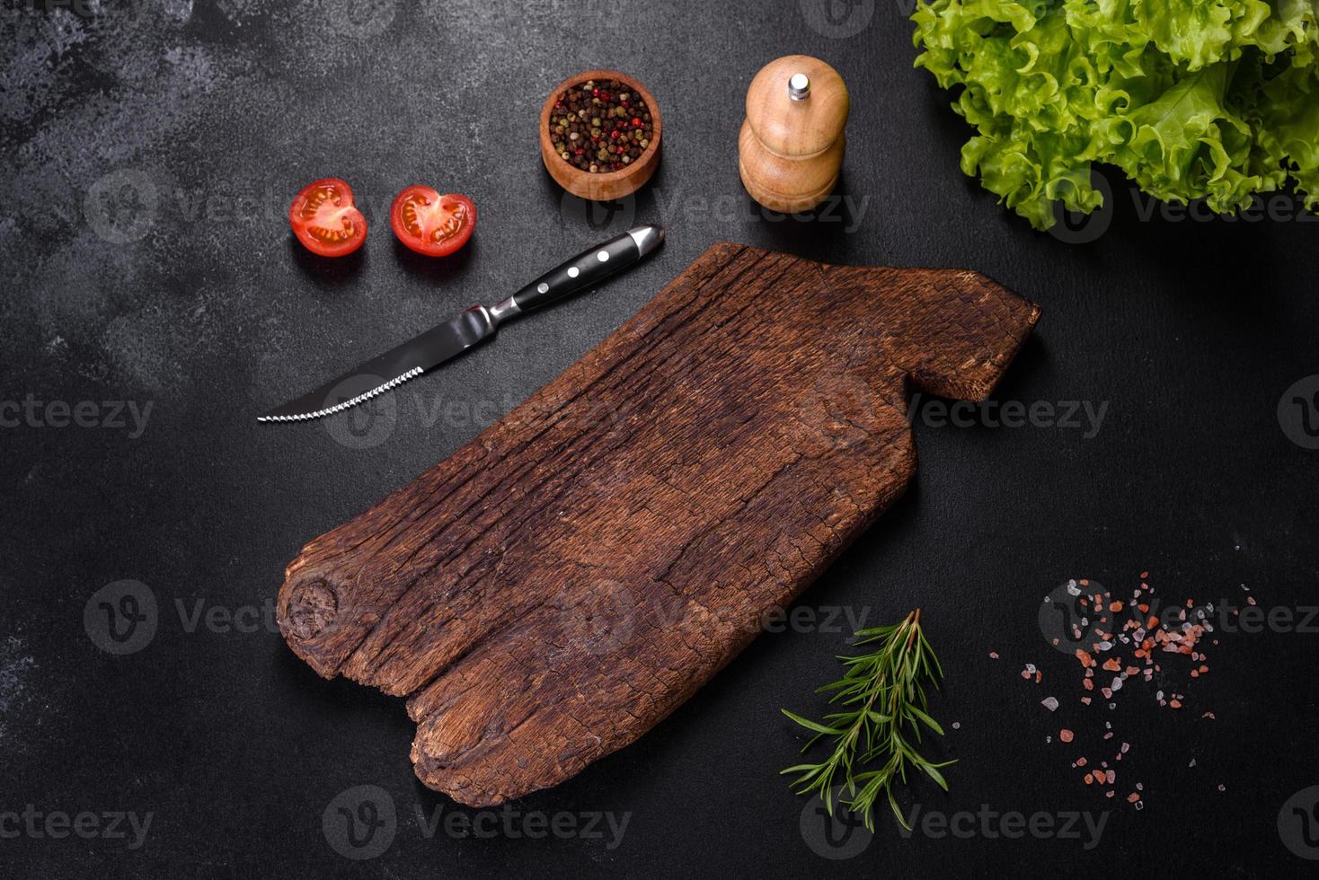 A wooden cutting board with a kitchen knife with spices and herbs photo