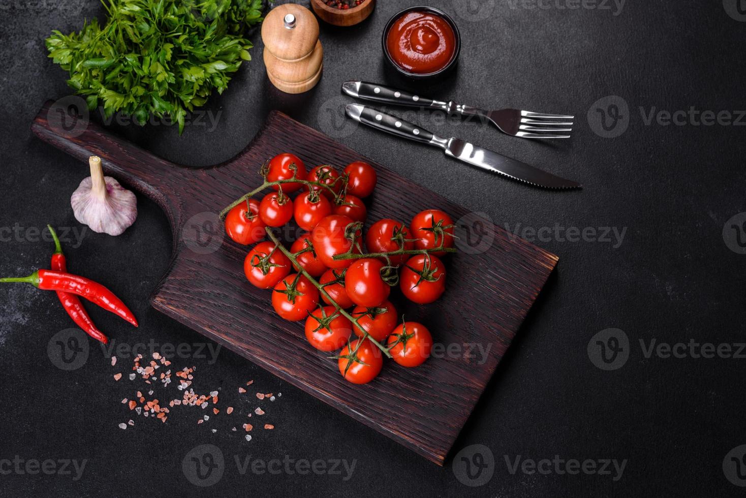 Fresh cherry tomatoes on a black background with spices photo