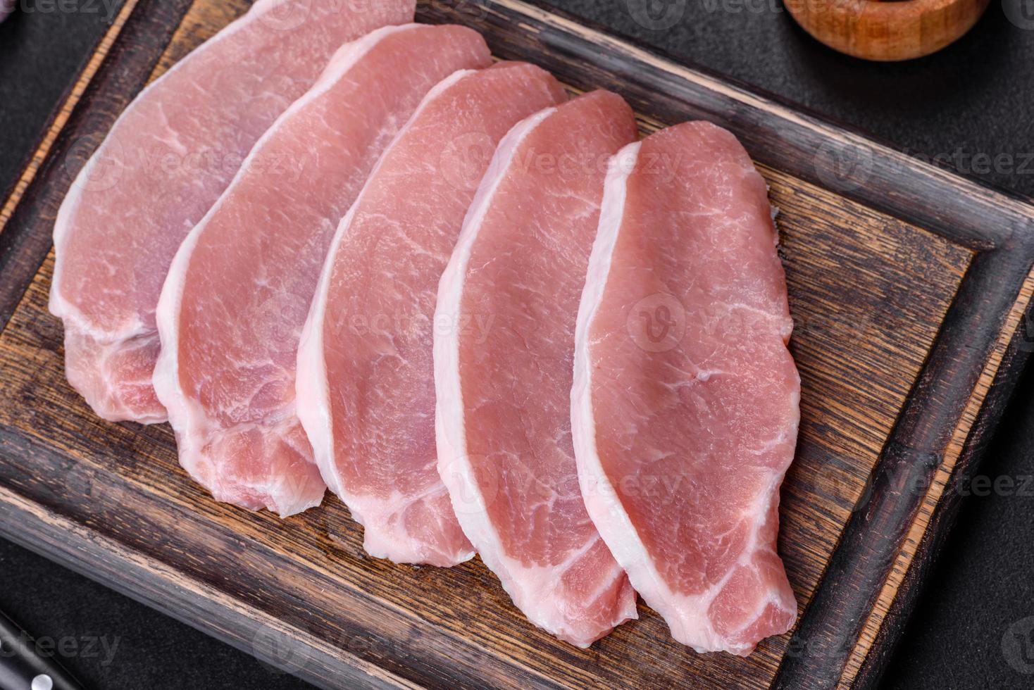 Raw fresh pork meat sliced on a wooden cutting board photo