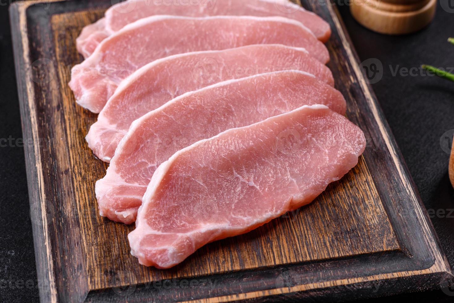 carne de cerdo fresca cruda cortada en una tabla de cortar de madera foto