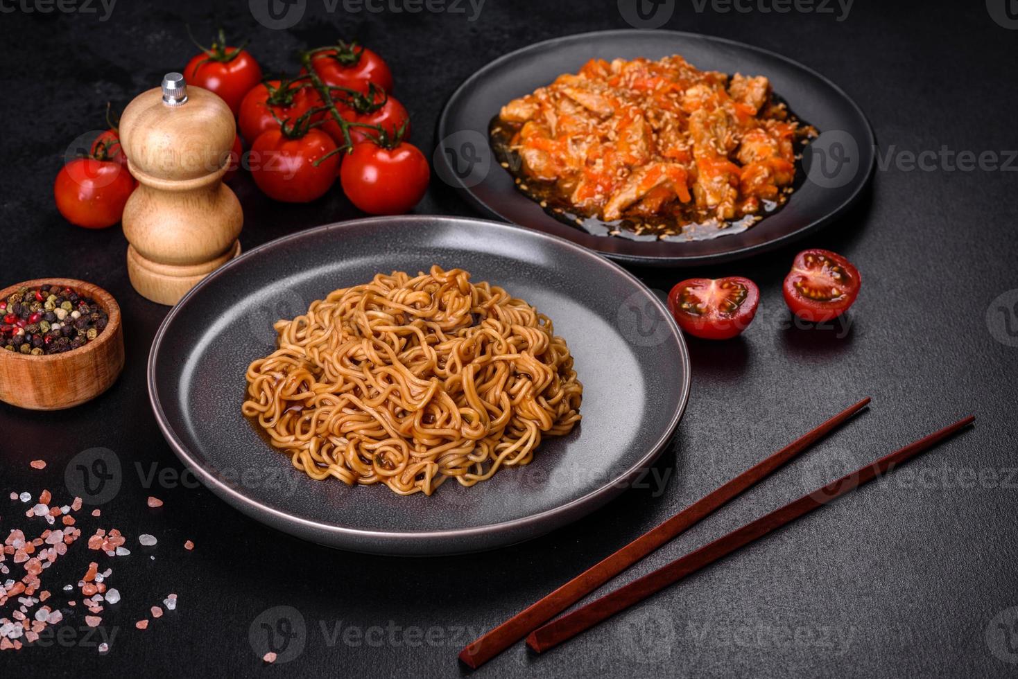 fideos tailandeses y plato de pollo sobre un fondo de hormigón negro con palillos chinos y espacio para copiar foto