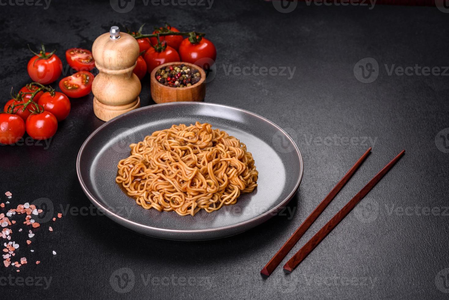 Buckwheat flour noodles with sauce, sesame, herbs and spices on a dark concrete background photo