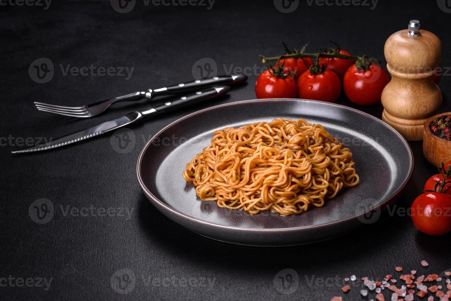 Buckwheat flour noodles with sauce, sesame, herbs and spices on a dark concrete background photo