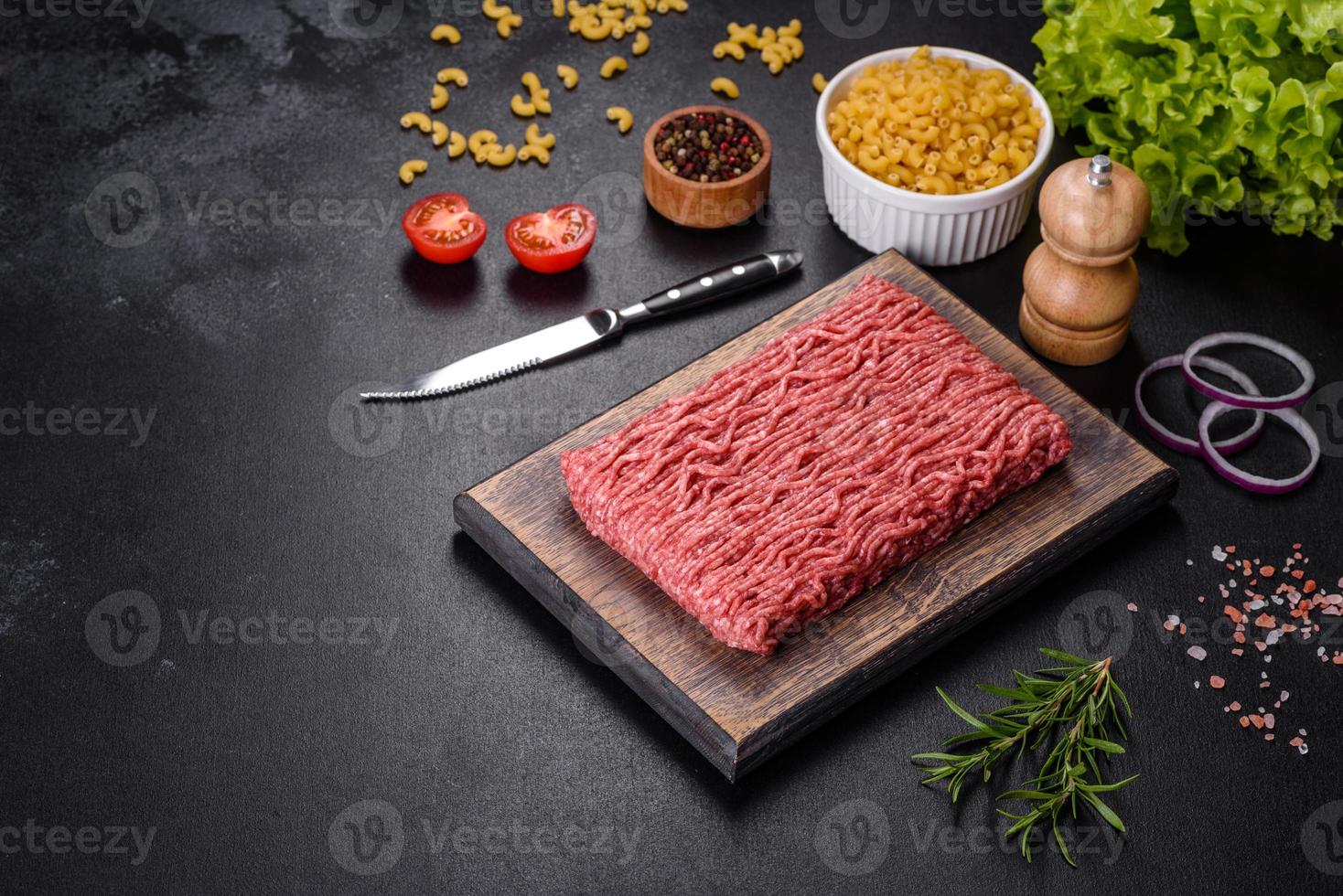 Fresh raw mince with spices and herbs on a dark concrete background photo
