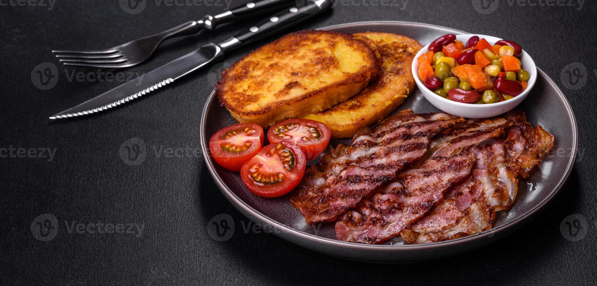 Slices of delicious grilled bacon with croutons fried in egg with spices, salt, vegetables and herbs photo
