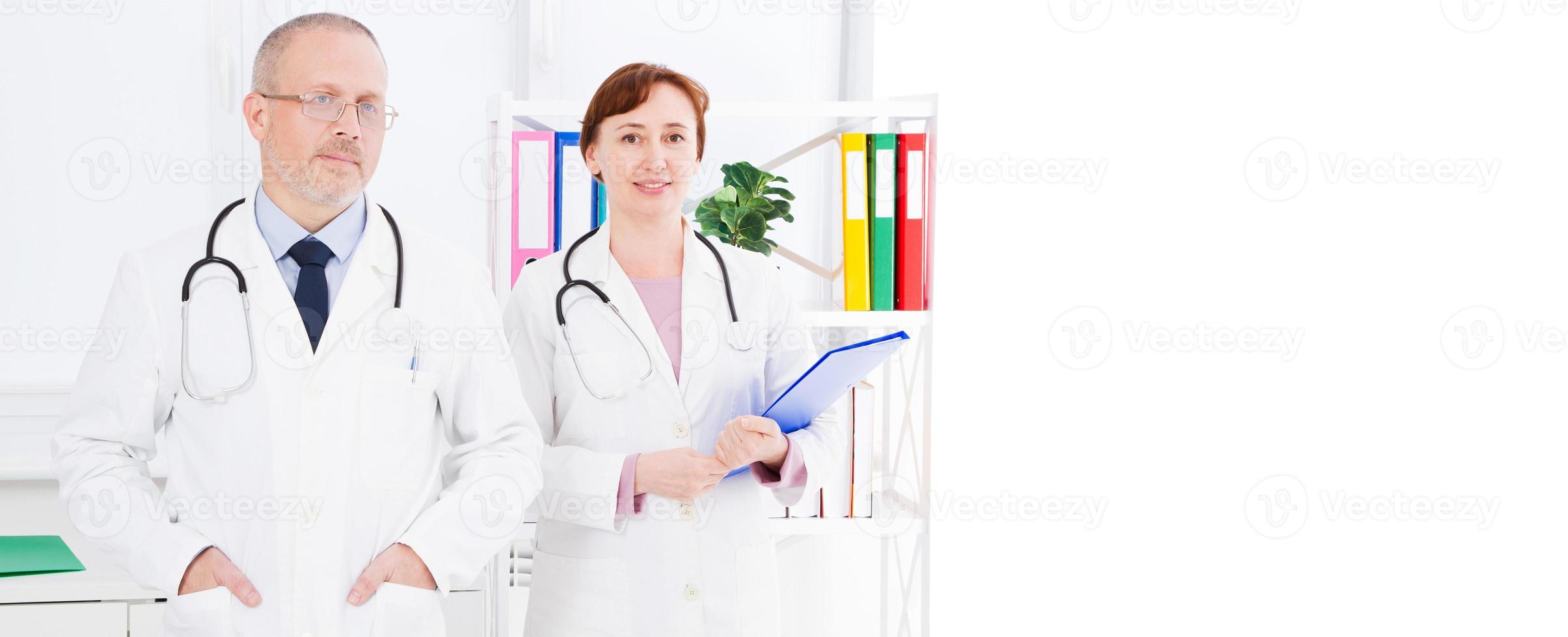 male and female doctors posing in medical office,they with stethoscopes,copy space, banner or billboard photo