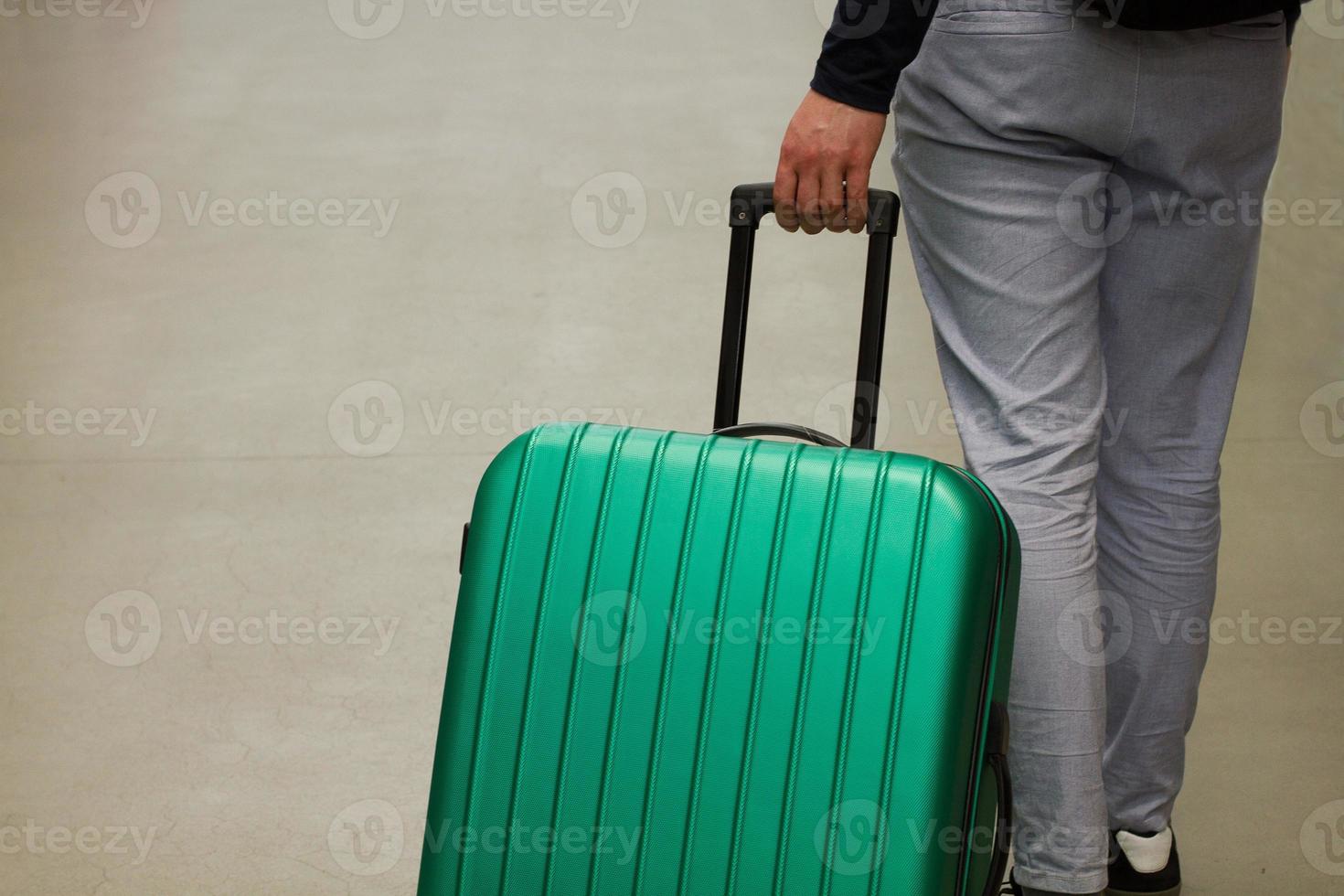 Waiting at the airport. The concept of summer vacation, a traveler with a suitcase in the waiting area of the airport terminal. Selective focus. photo