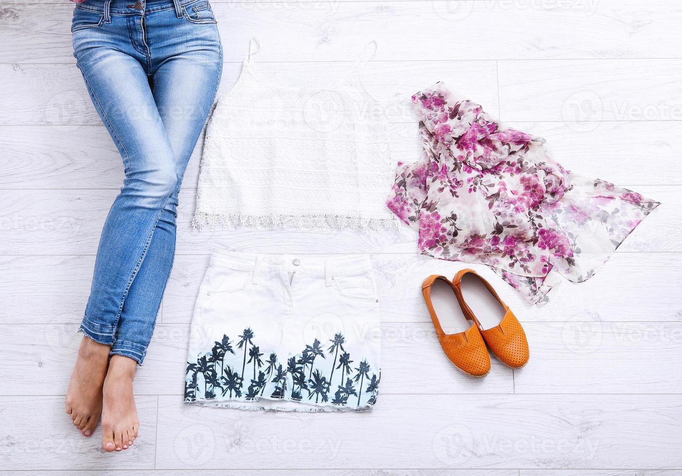 Stylish outfit with accessories and female legs on white wooden background. Top view and copy space photo