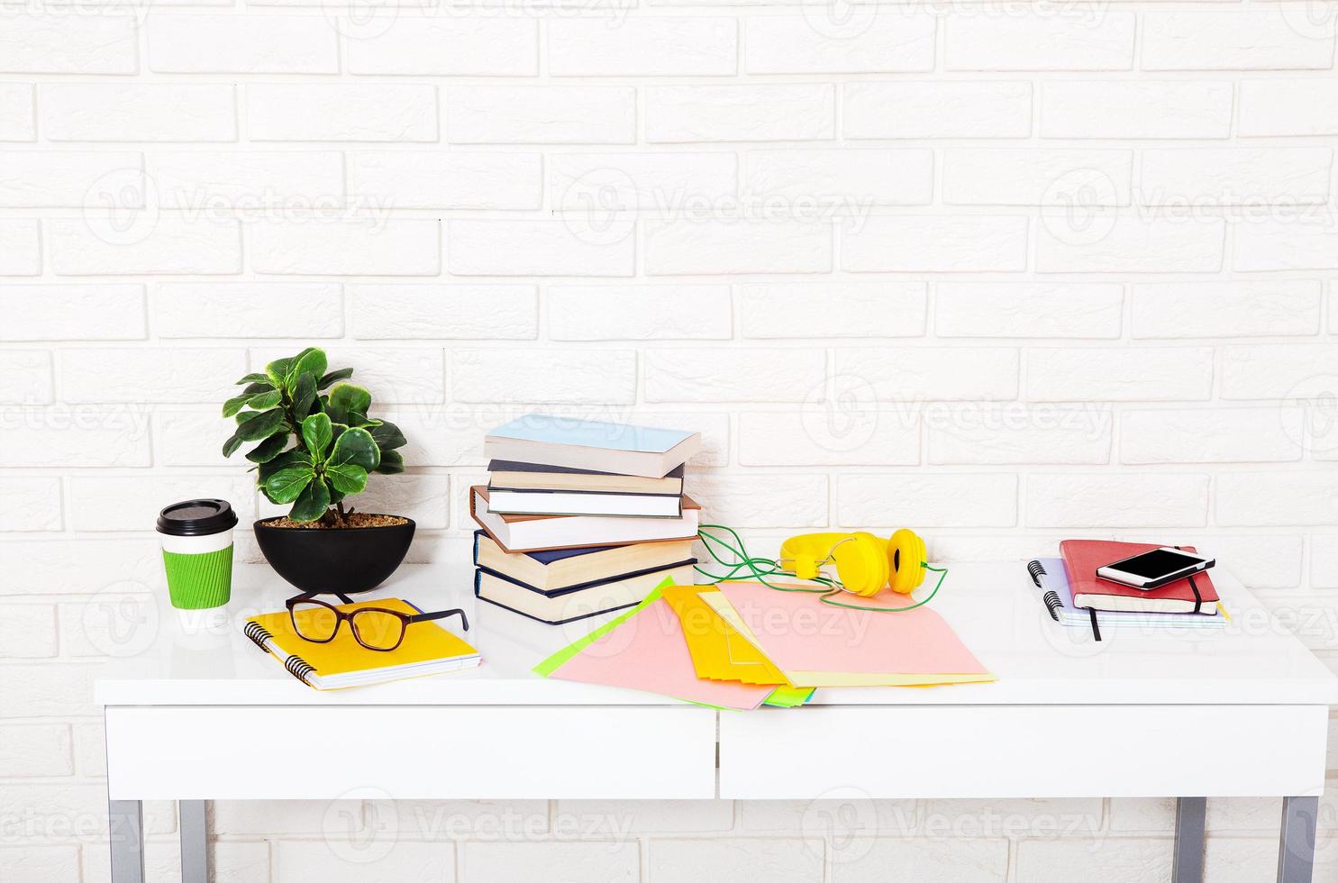 Workplace with cup of coffee and education stuff in the room. Brick wall and colorful papers. selective focus photo