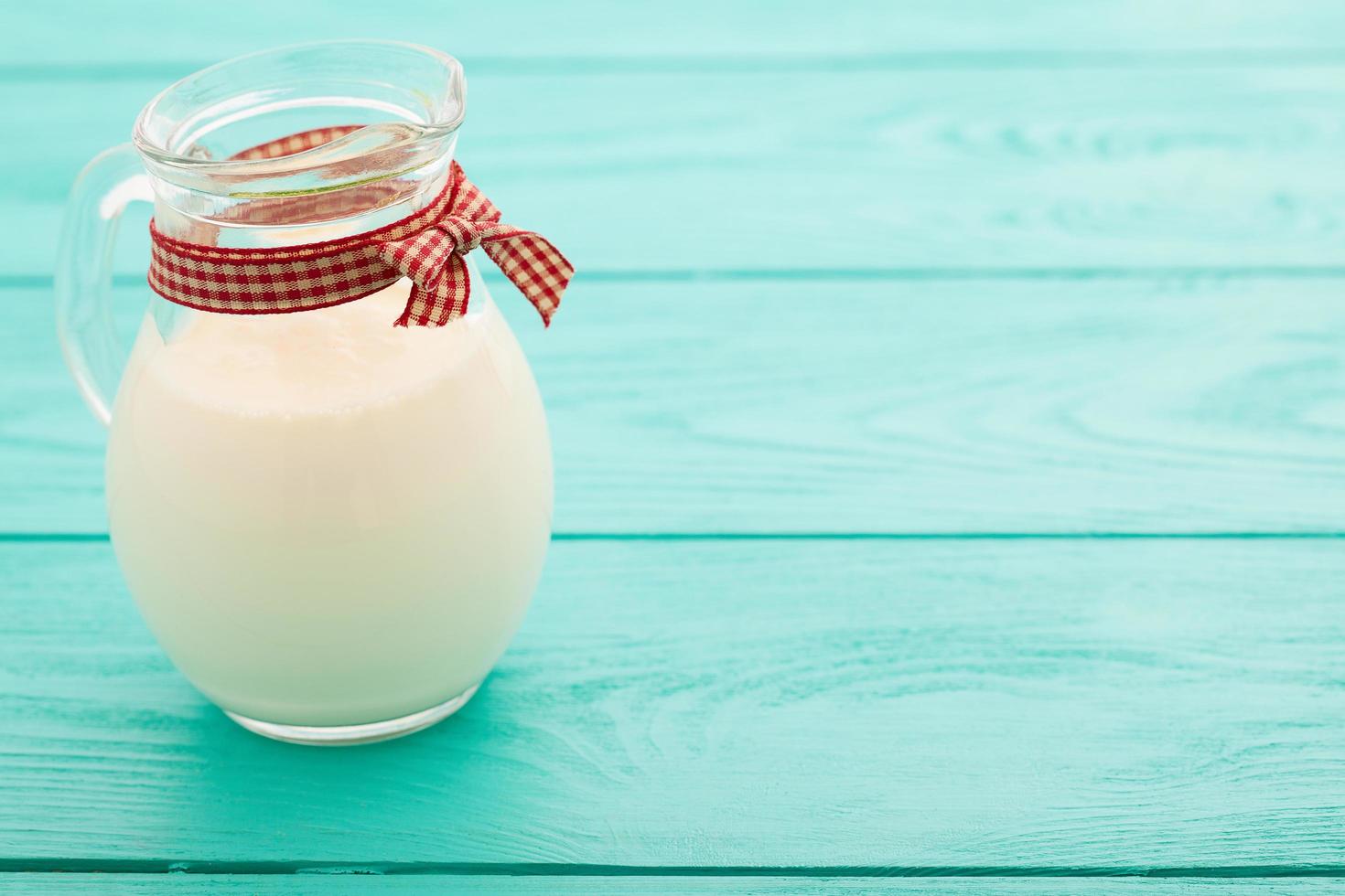 Breakfast with jug of milk and plaid ribbon on blue wooden background. Top view and copy space. Selective focus photo