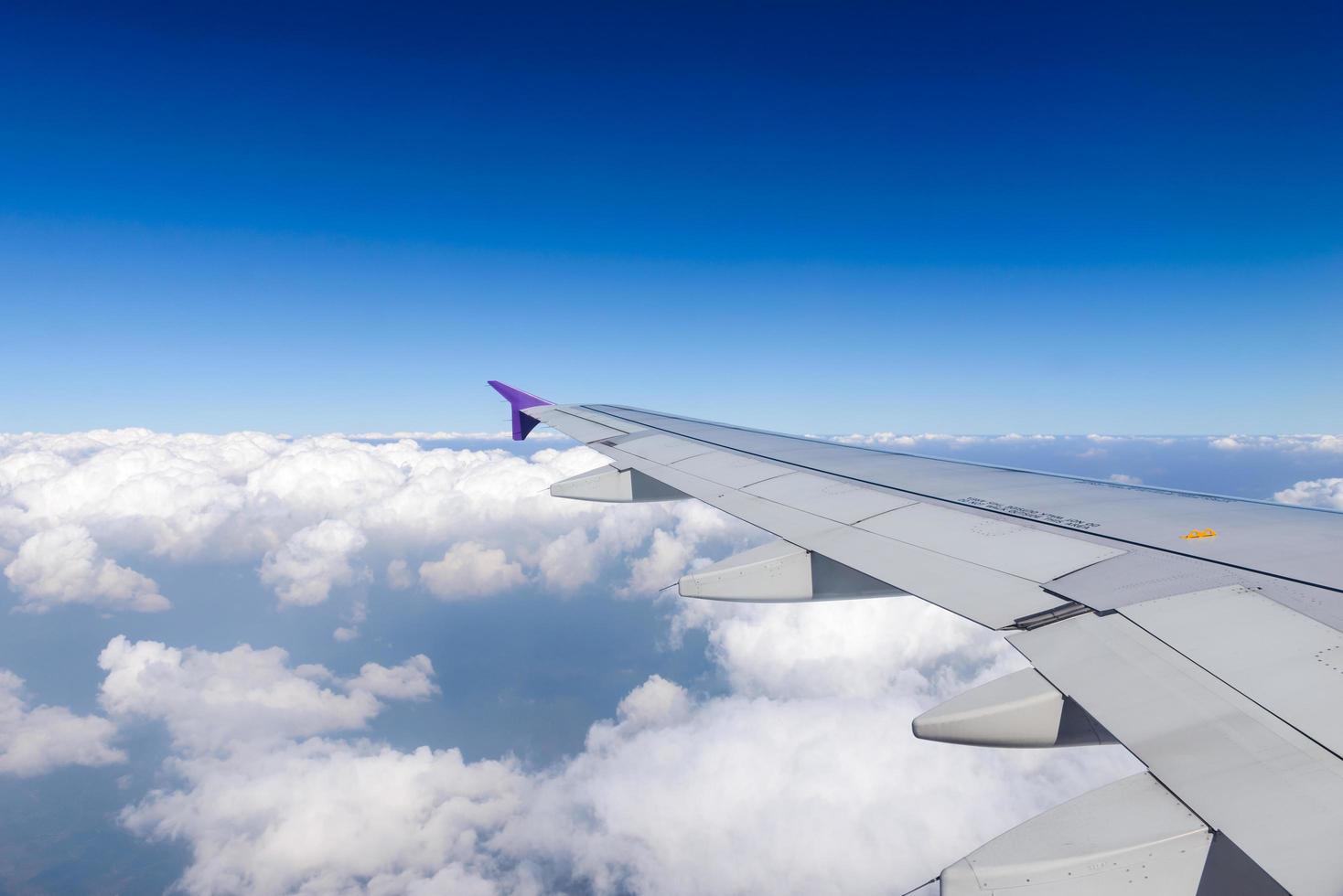 Wing of the plane flying above the clouds. View from the window of an airplane photo