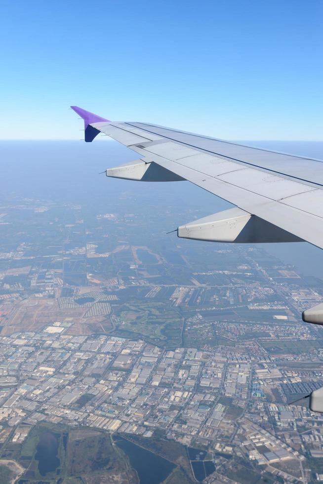 Wing of the plane flying above the city. View from the window of an airplane photo