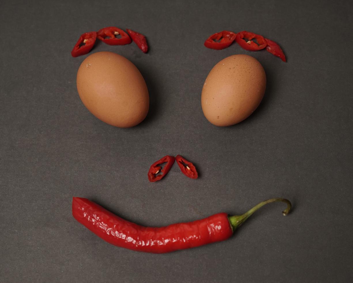The combination of fresh tomatoes, red chilies and eggs forms a smiling face. Cooking ingredients ready to be served. focus blur, background inspiration. black and red color combination. photo