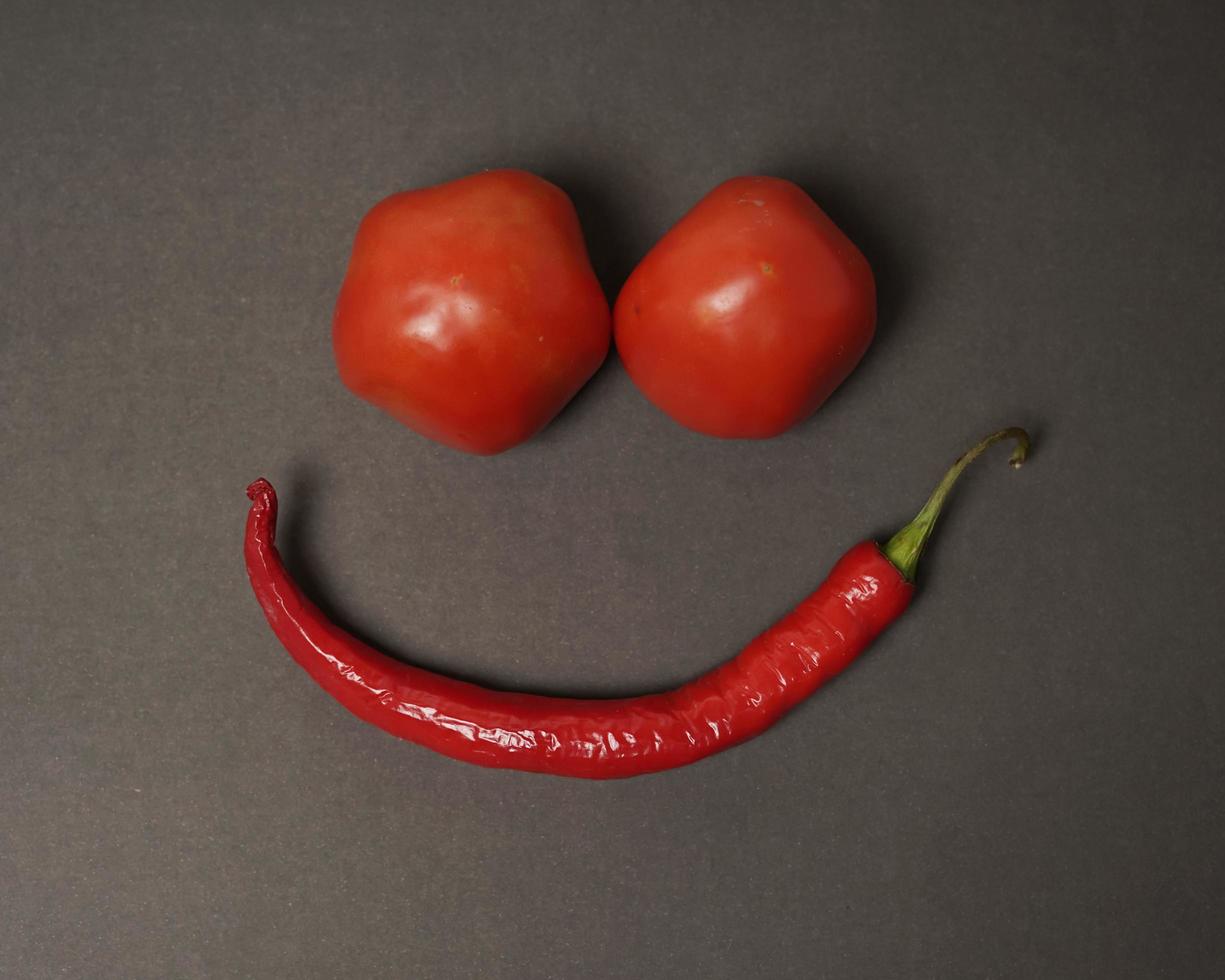 The combination of fresh tomatoes, red chilies and eggs forms a smiling face. Cooking ingredients ready to be served. focus blur, background inspiration. black and red color combination. photo