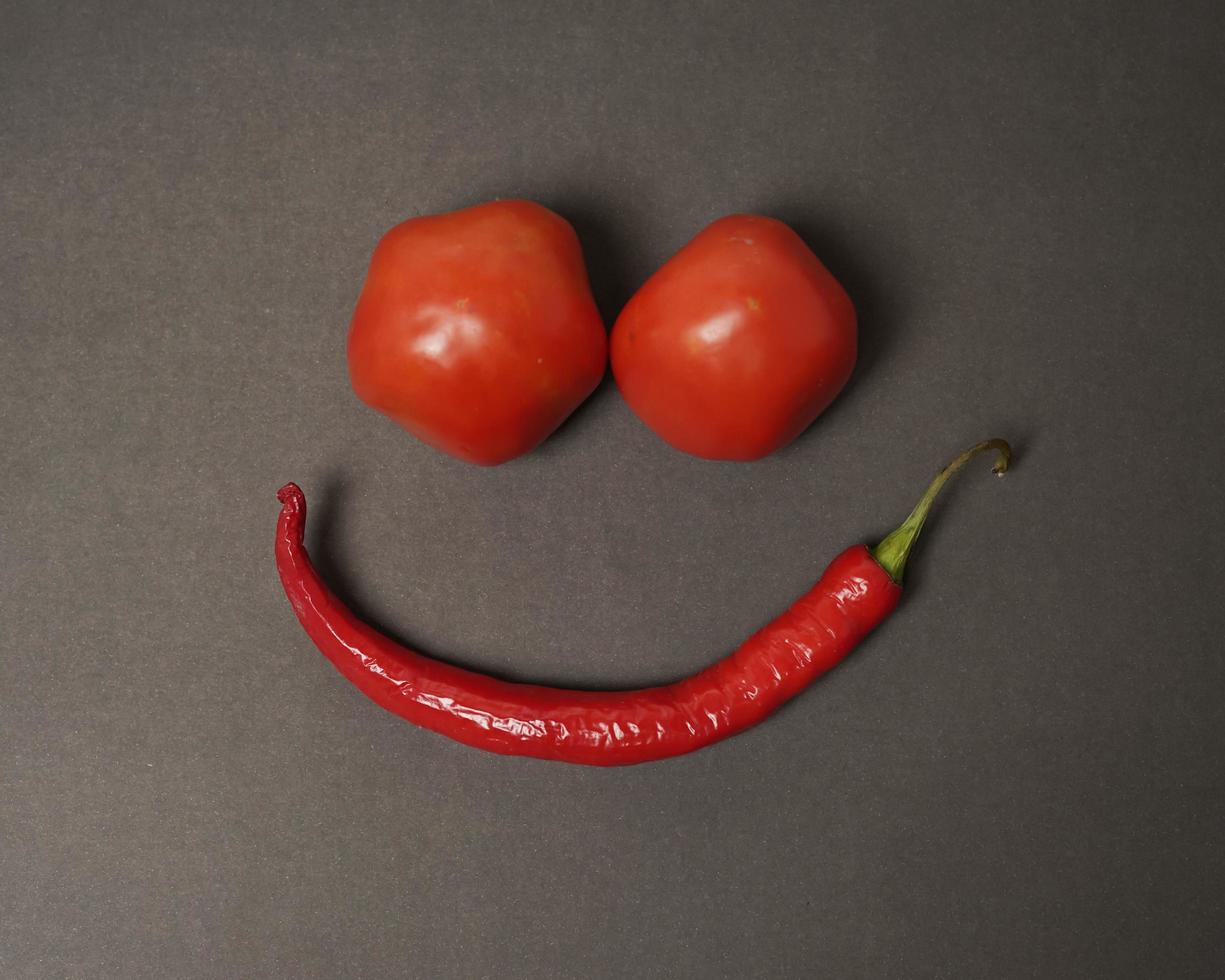 The combination of fresh tomatoes, red chilies and eggs forms a smiling face. Cooking ingredients ready to be served. focus blur, background inspiration. black and red color combination. photo