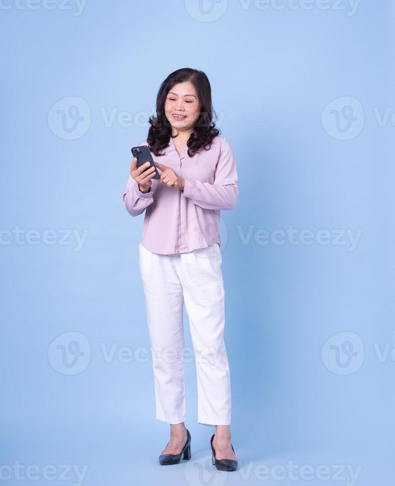imagen completa de una mujer asiática de mediana edad con fondo azul foto