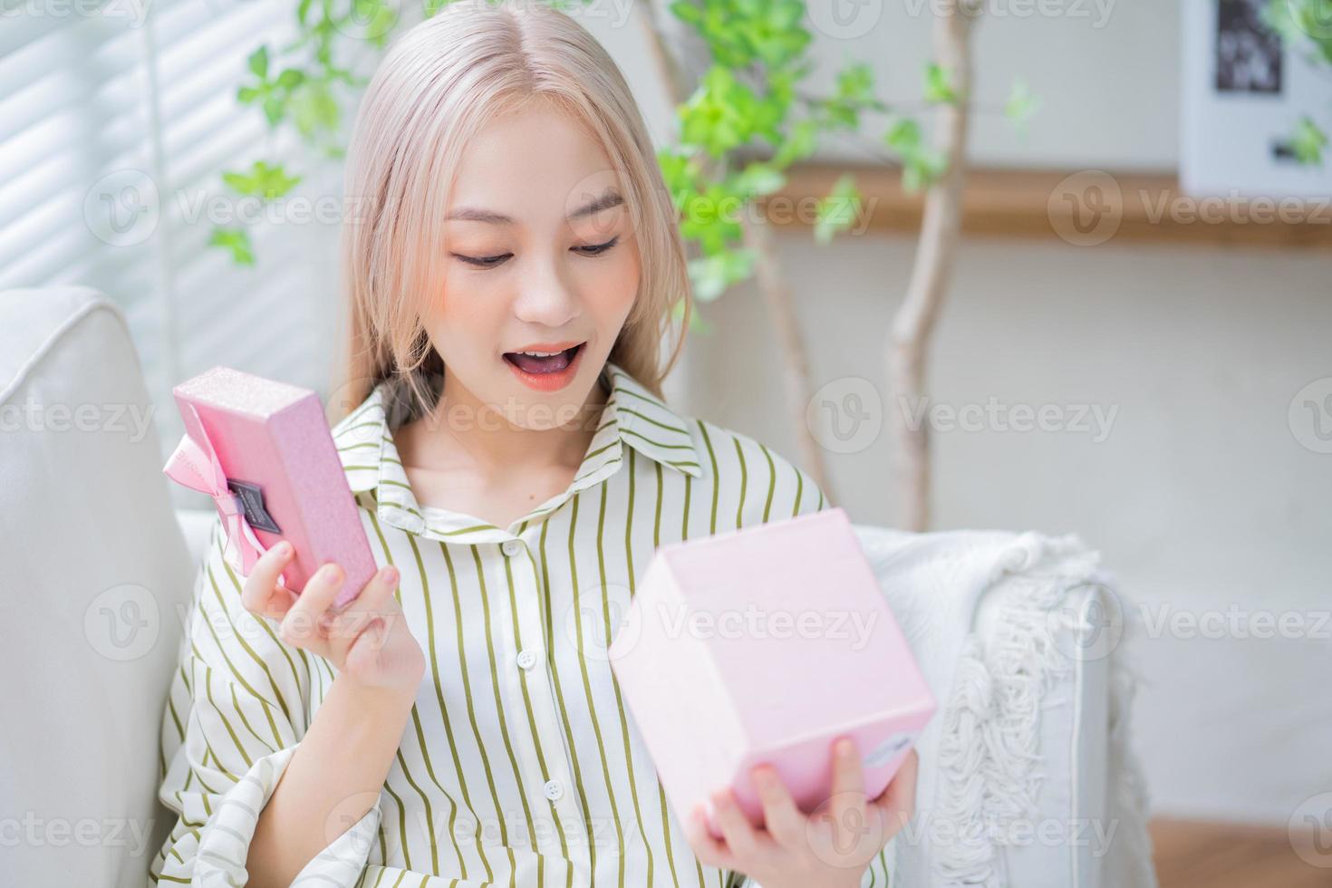 Young Asian woman holding gift box at home photo