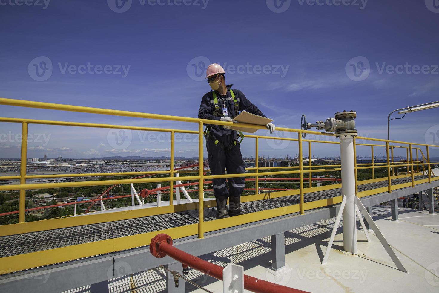 trabajador masculino inspección techo visual tanque de almacenamiento aceite fondo ciudad. foto