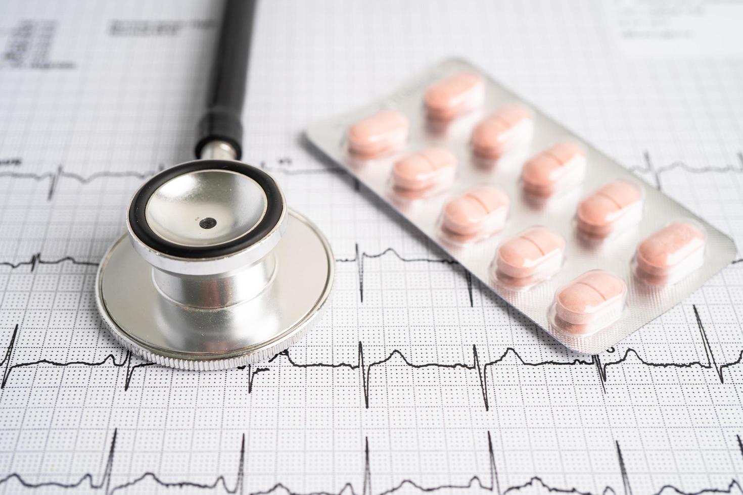 Stethoscope on electrocardiogram with capsule pill, heart wave, heart attack, cardiogram report. photo