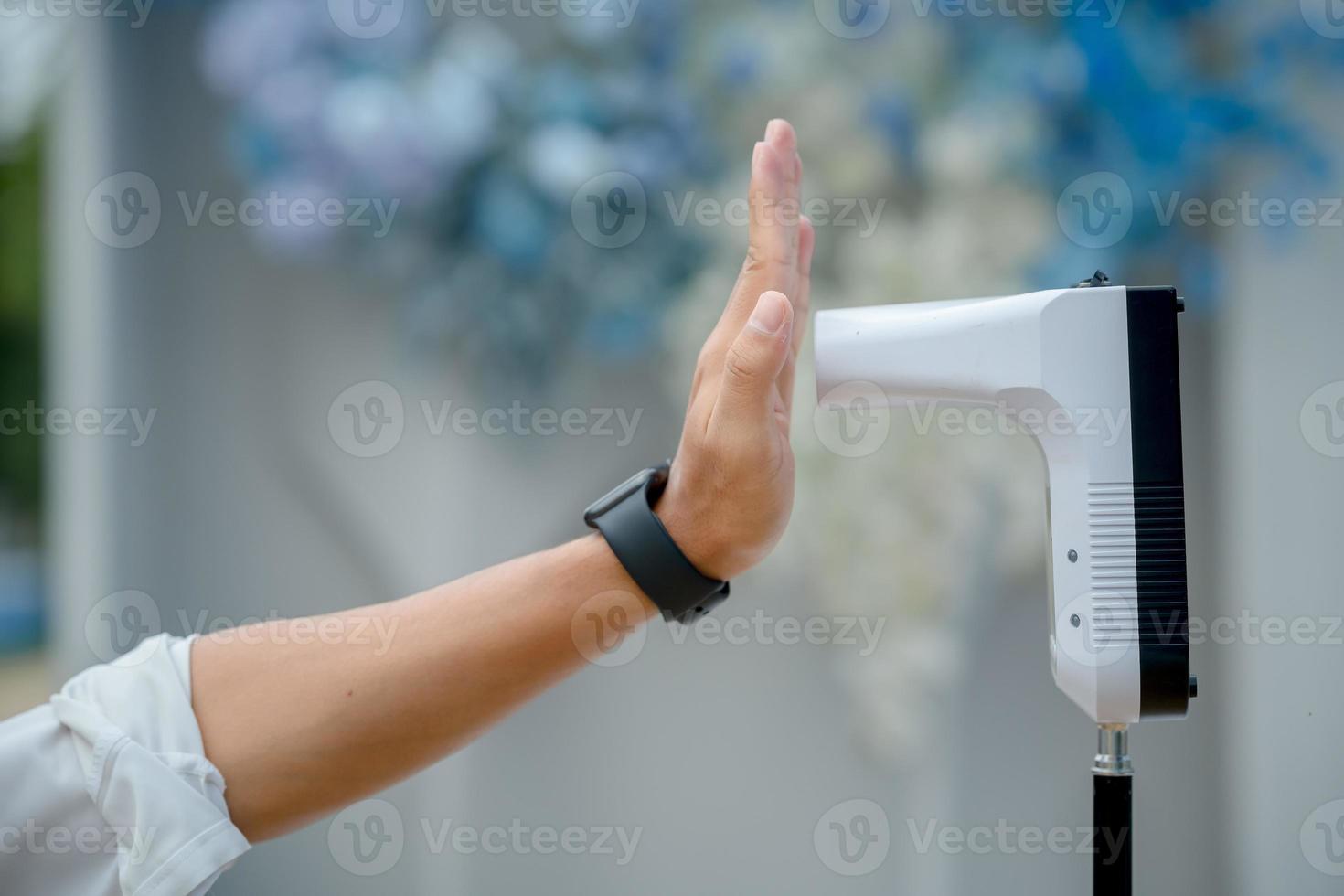 levante la mano a la entrada con un termómetro digital. termómetro antes de entrar a la boda la situación del virus covid-19 foto