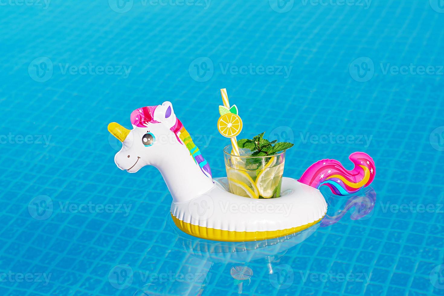Fresh coctail mojito on inflatable white unicorn toy at swimming pool. Vacation concept. photo
