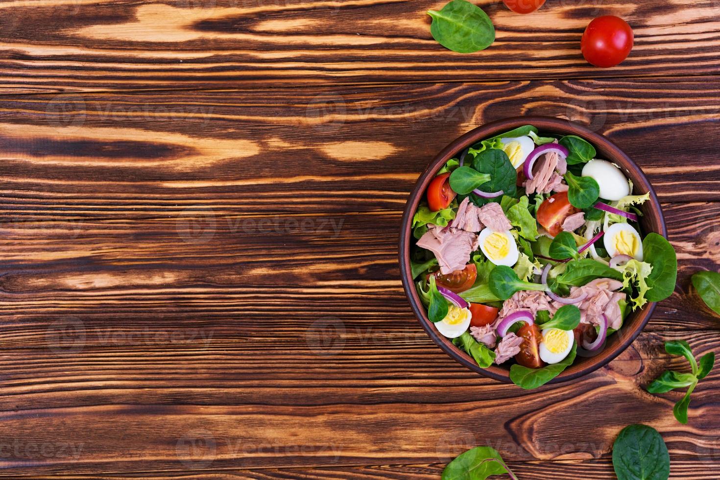 Salad with tuna, tomatoes, quail eggs, asparagus and onions on wooden background photo
