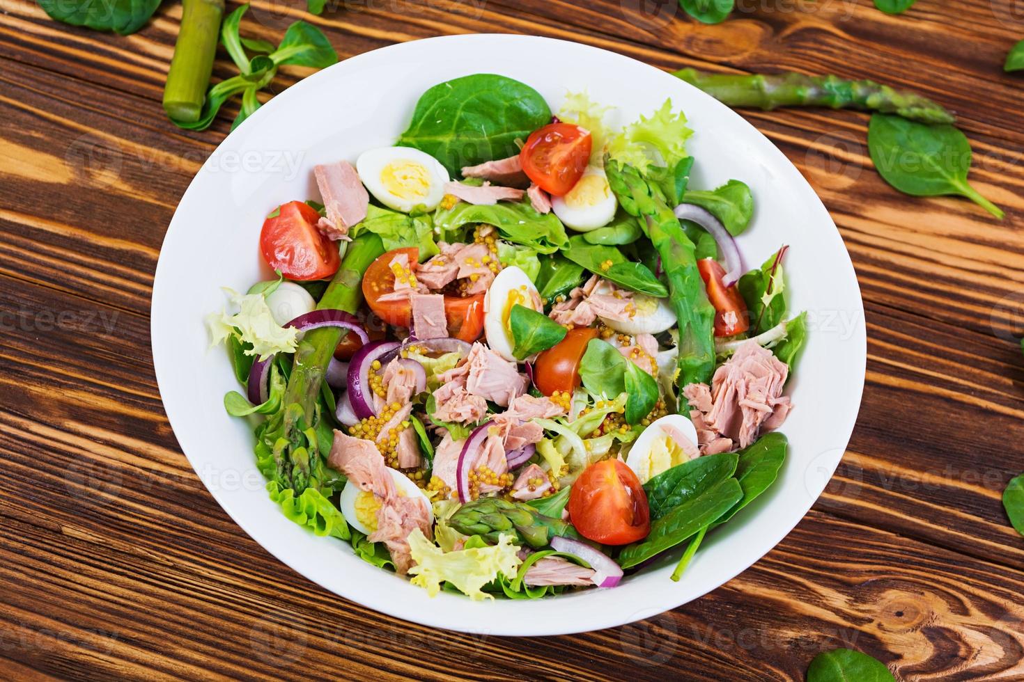 Salad with tuna, tomatoes, quail eggs, asparagus and onions on wooden background photo