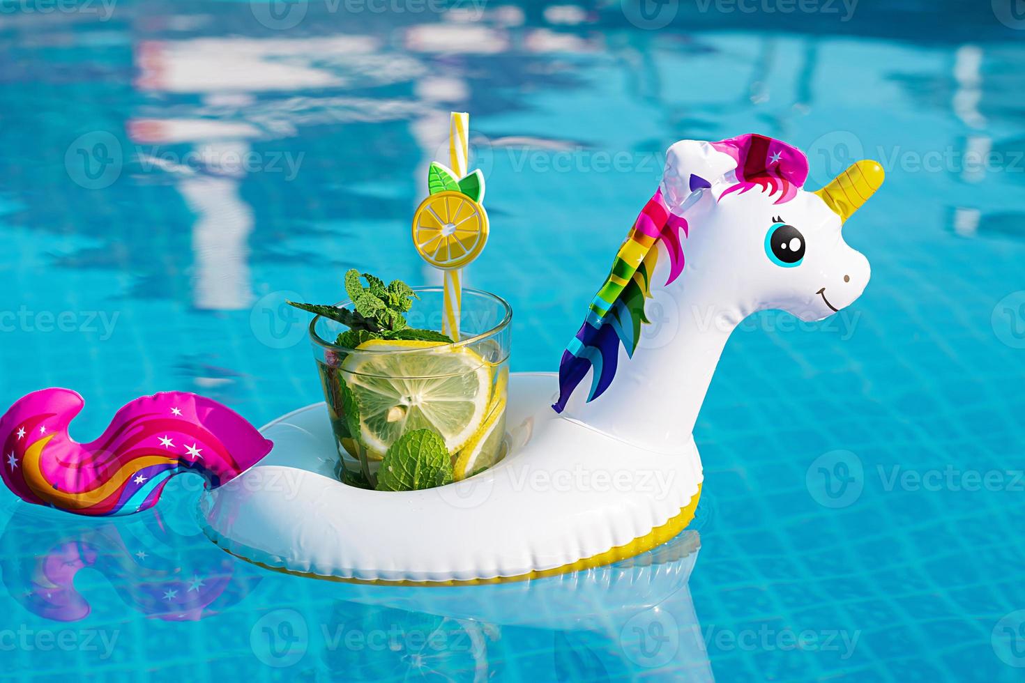 Fresh coctail mojito on inflatable white unicorn toy at swimming pool. Vacation concept. photo