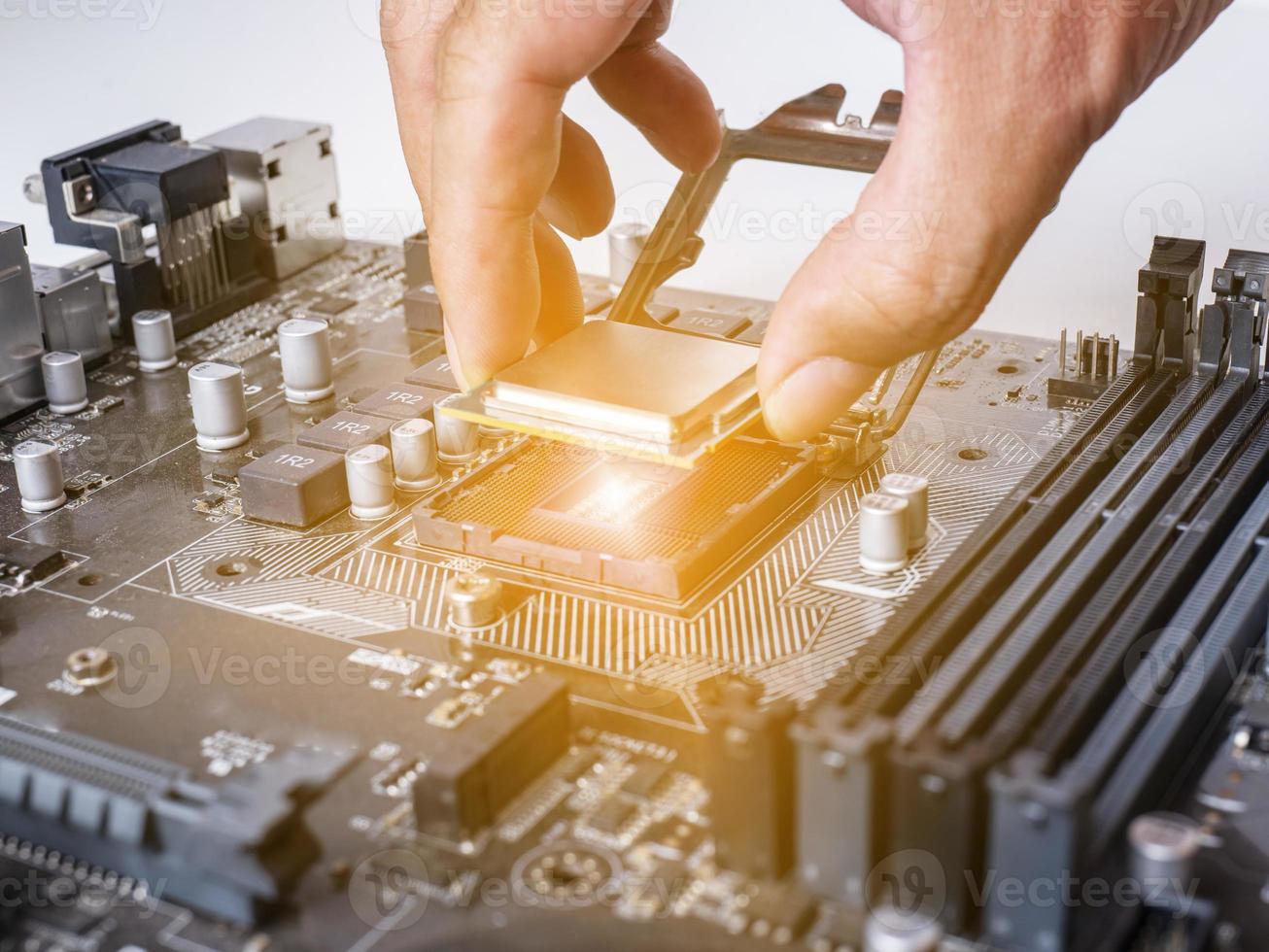 Hold the CPU handle and insert it into the CPU slot on the motherboard. It's an old motherboard, lots of dust. Put orange light on the cpu slot. There is a RAM slot next to it. There is a capacitor. photo