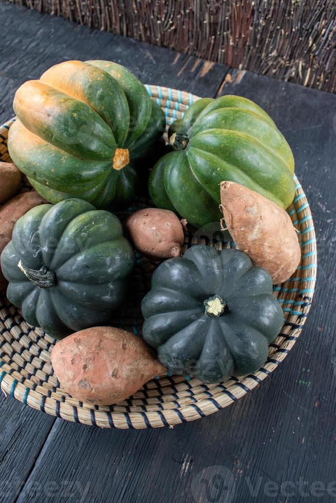 cosecha de otoño de batatas y calabazas en una canasta plana foto