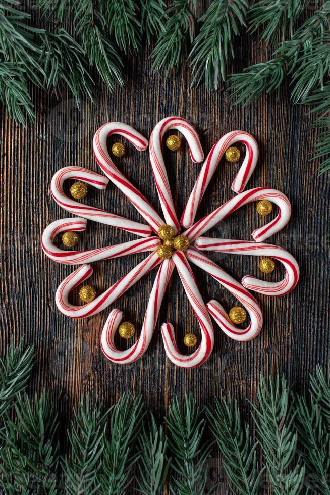 bastones de caramelo en un diseño de flores con bolas de oro brillante con borde de árbol verde con espacio de copia plano foto