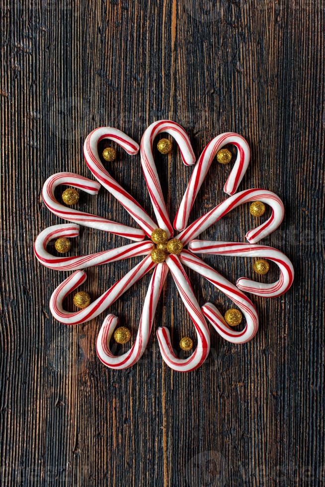 candy canes in a flower design with glitter gold balls on rustic wood table flat lay photo