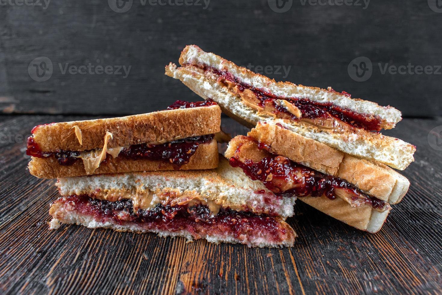 Sándwiches desordenados de mantequilla de maní y mermelada cortados por la mitad en una pila foto