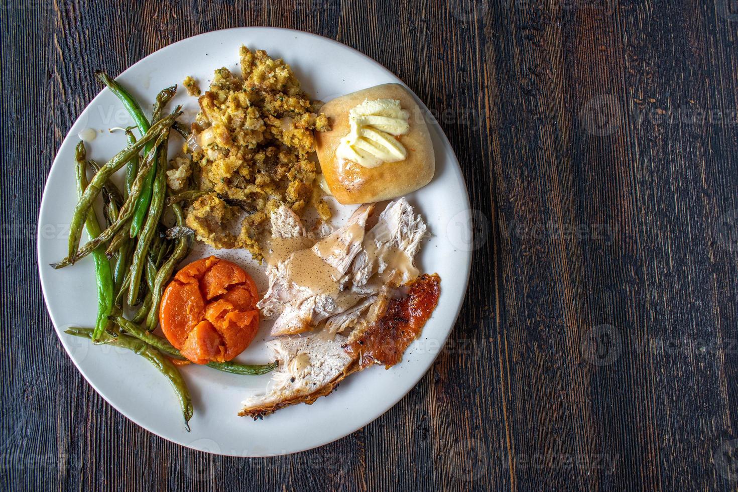 plated flat lay white turkey meat with vegetable sides, buttered bread, and gravey photo