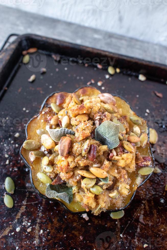 roasted acorn squash bowls filled with bread stuffing, nuts, and herbs on baking sheet photo