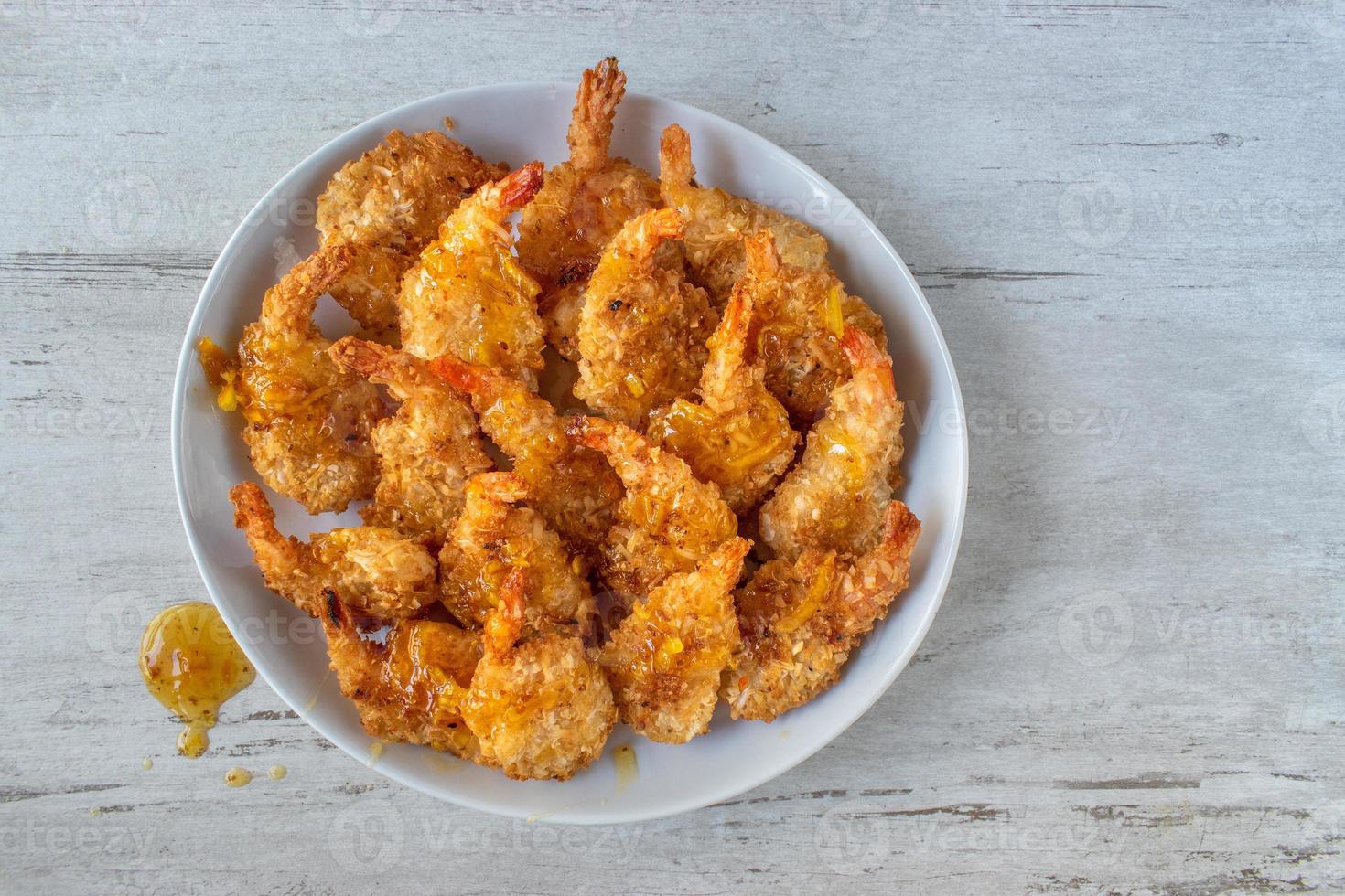 Fried Coconut Shrimp with tails drizzled with sauce flat lay photo