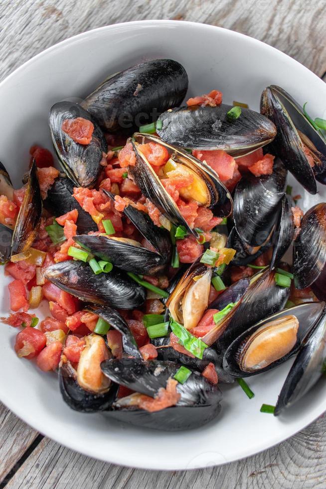 Plato de marisco mediterráneo al vapor de mejillones con tomates y cebollas verdes endecha plana foto