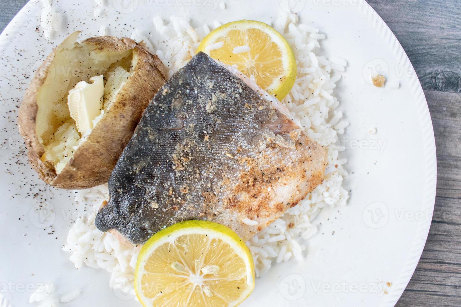 filete de salmón chapado con rodajas de limón sobre cama de arroz blanco plano foto