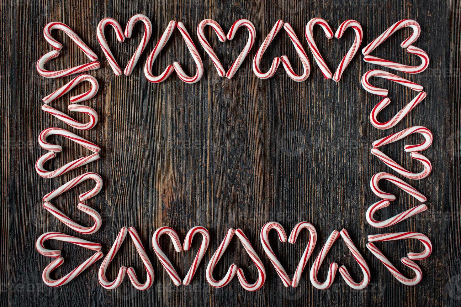 borde de corazón de bastón de caramelo de dirección alterna con espacio de copia en una mesa de madera rústica plana foto