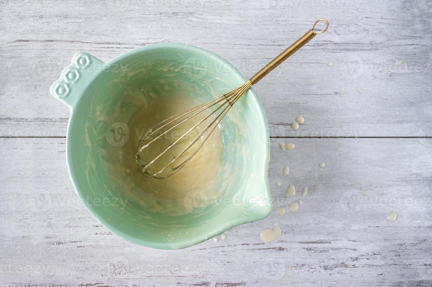 Remnants of cake batter in a bright bowl with drips flat lay photo