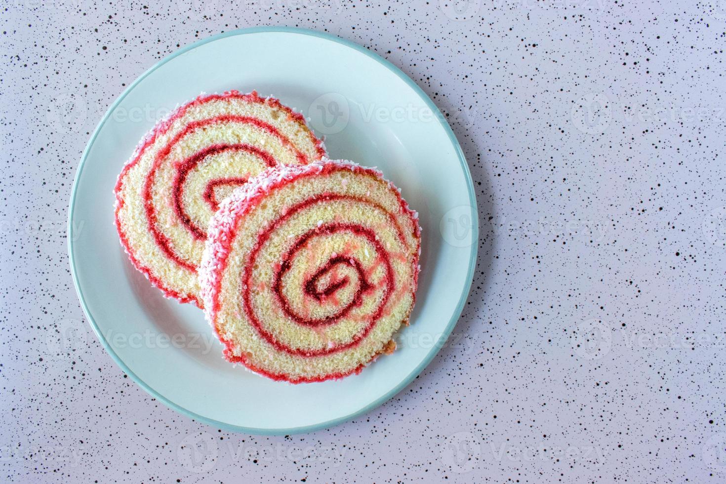 Sliced rounds of jelly roll cake pieces on bright colorful background flat lay photo