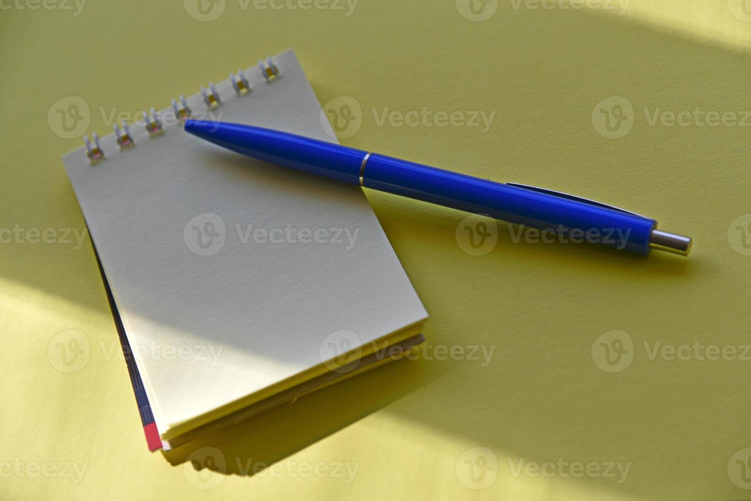 Blue fountain pen and notepad on a yellow background photo