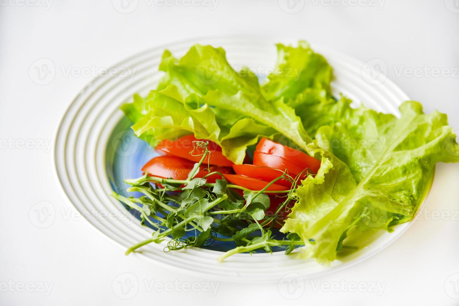 Salad on a white plate tomatoes greens and peas. White background. photo