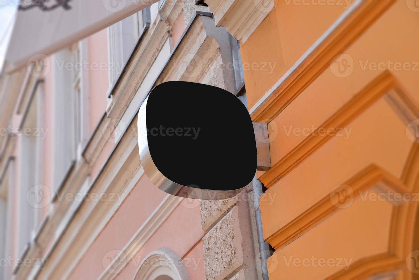 Small rounded black sign on the facade of the building in the main street. Blank for company logo promotion photo