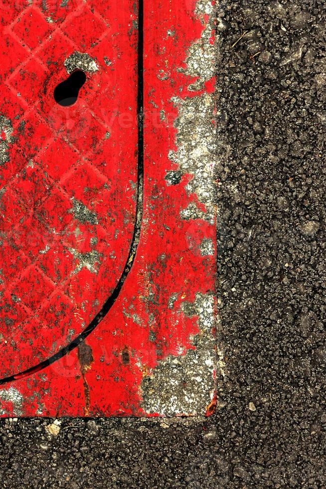 Red manhole cover smiling in the asphalt. Vertical image. photo