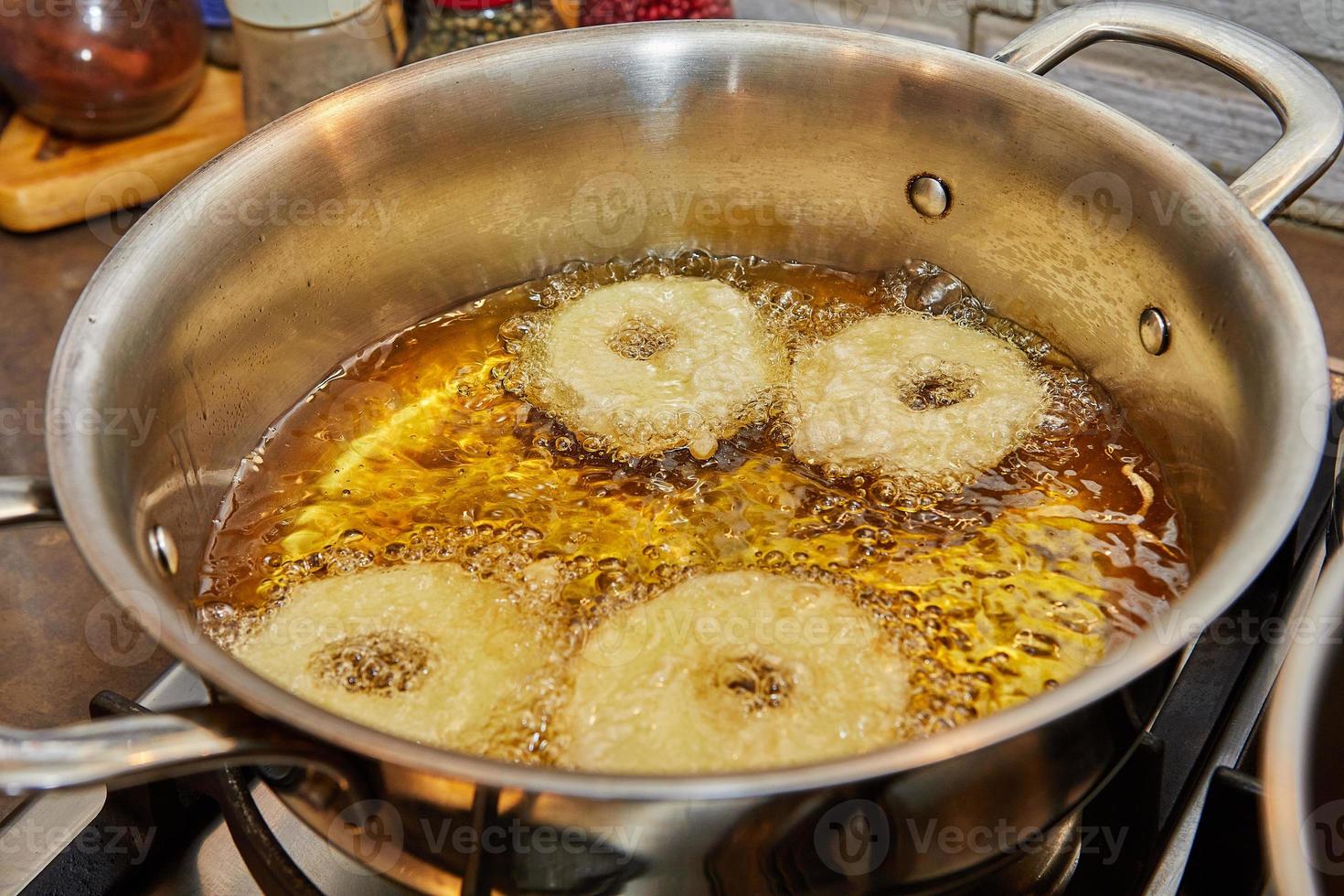 cocinar panqueques de manzana. donut de manzana en aceite hirviendo foto