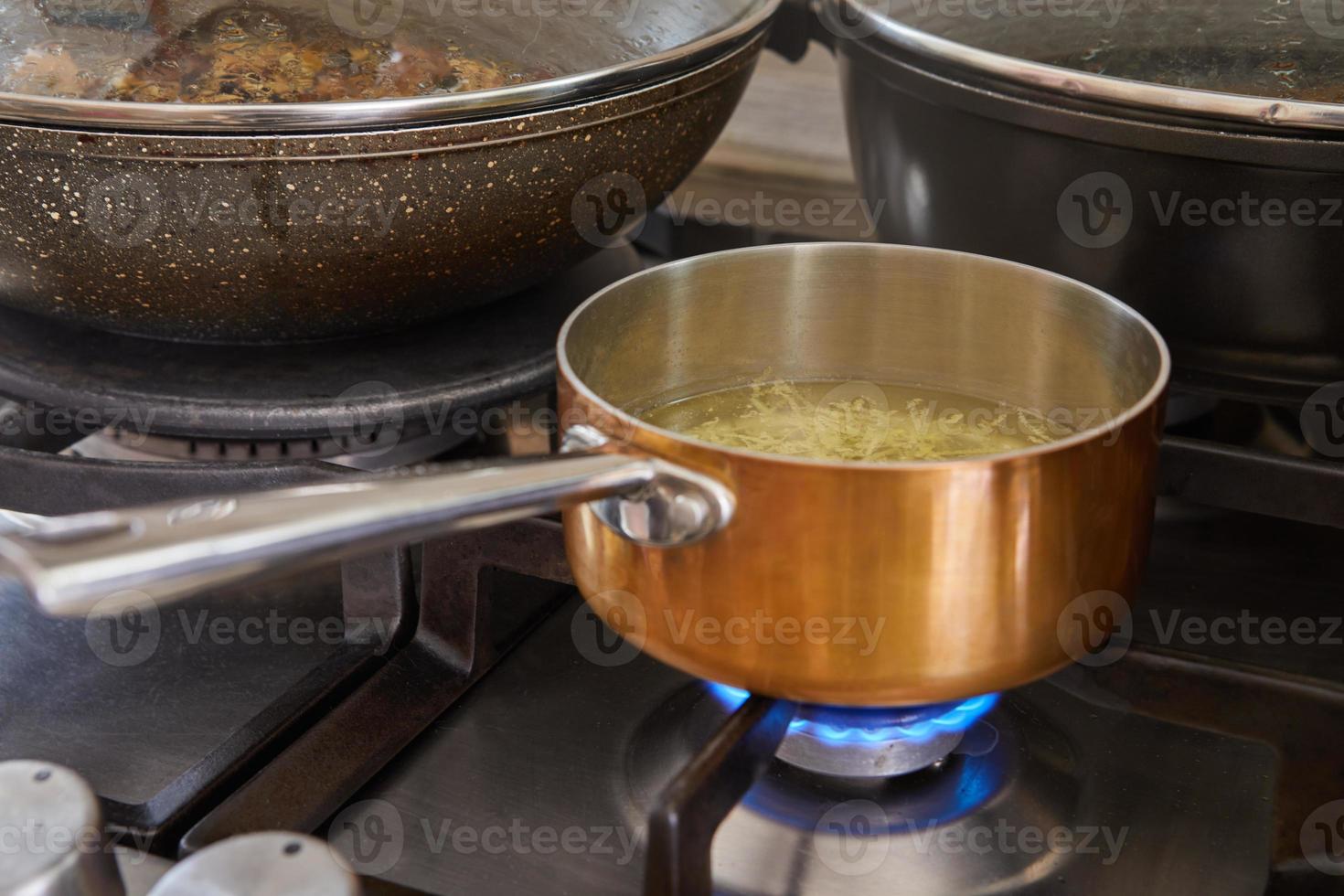 Saucepan with handle from copper and stainless steel on gas stove fire photo